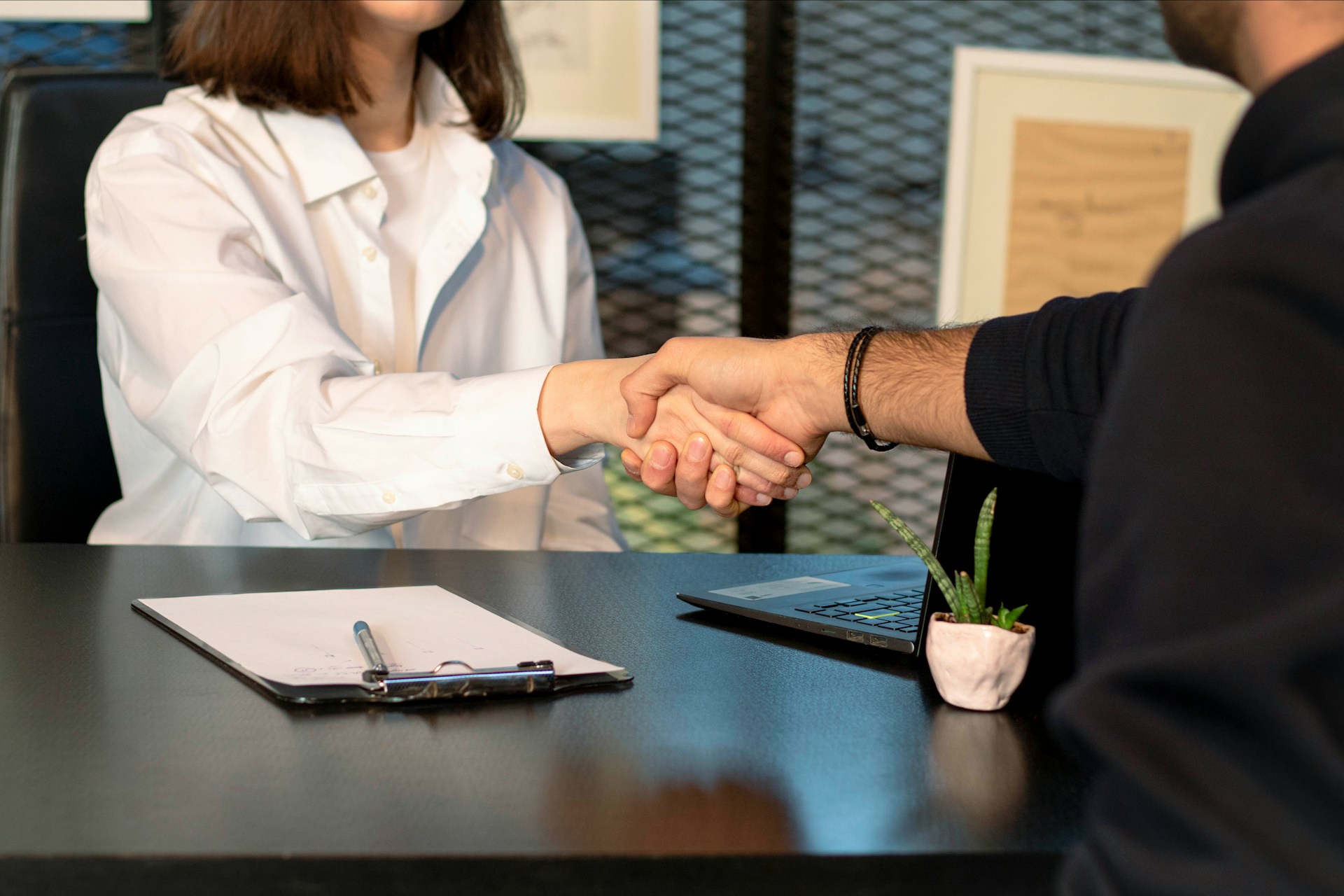 Two people shaking hands over a table