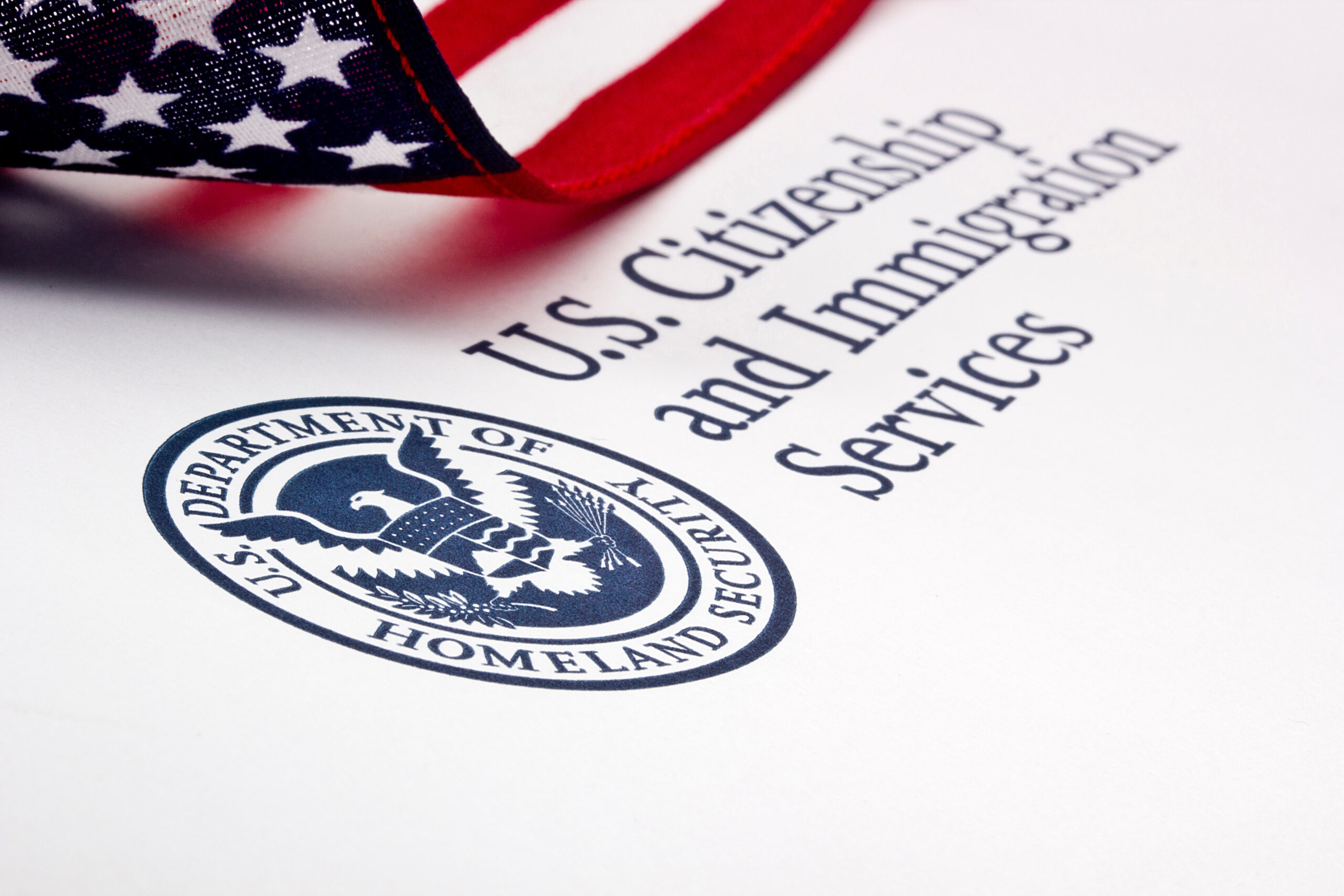 The logo of USCIS on a document with a flag.