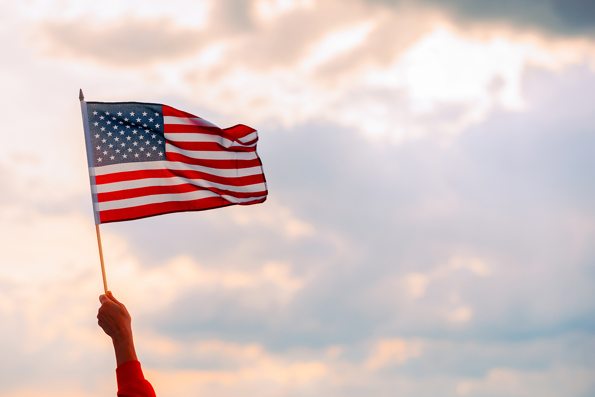 A person waving a US flag outside.