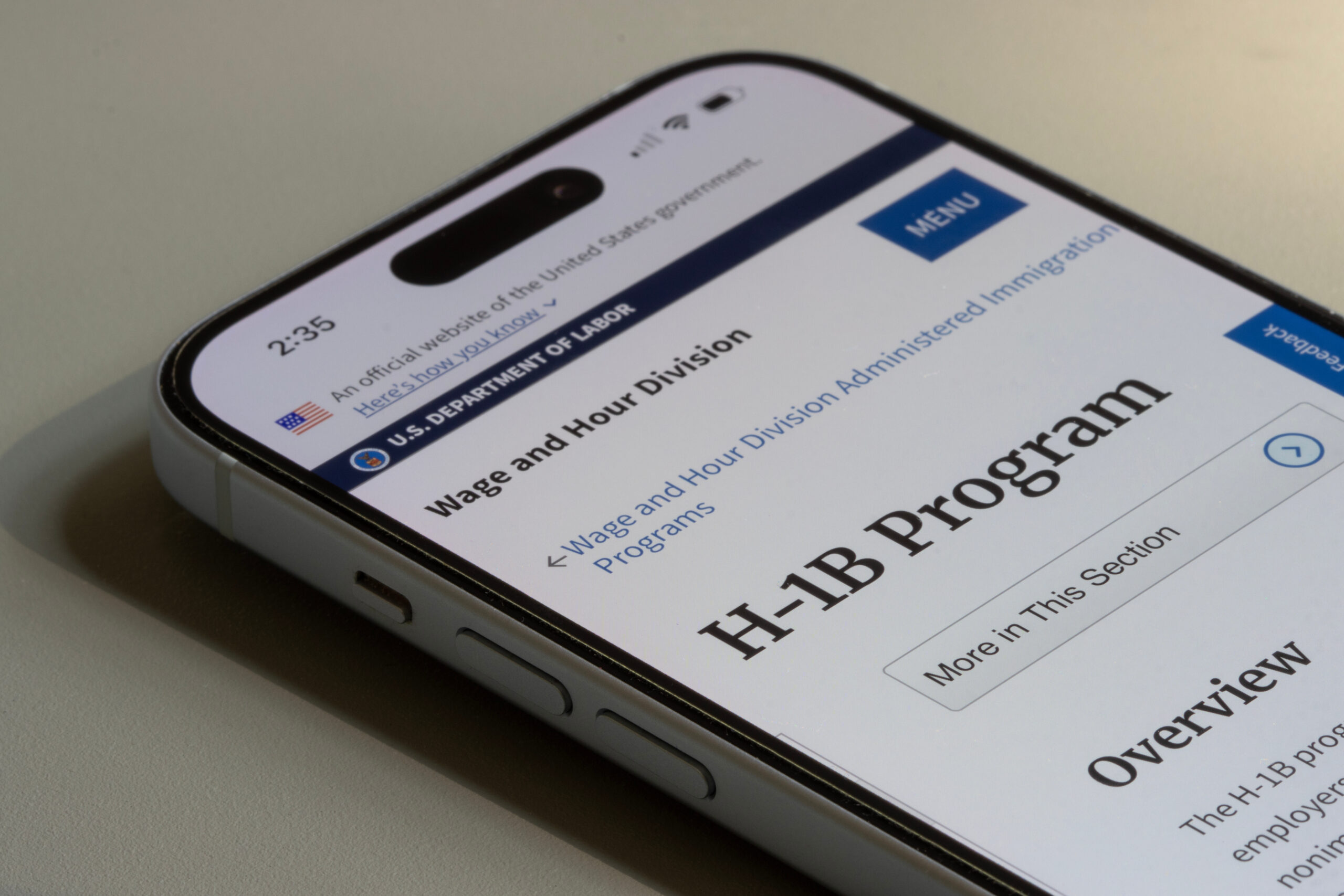 A phone with the H-1B Program page.